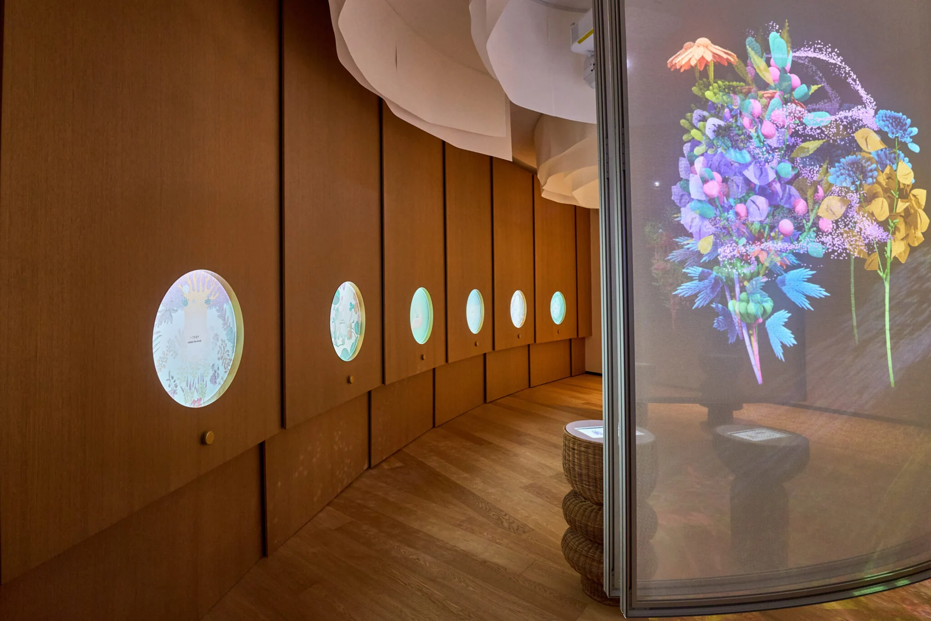 Circular displays along a wooden gallery wall beside a colourful digital flower installation at Poland's Expo 2025 pavilion.
