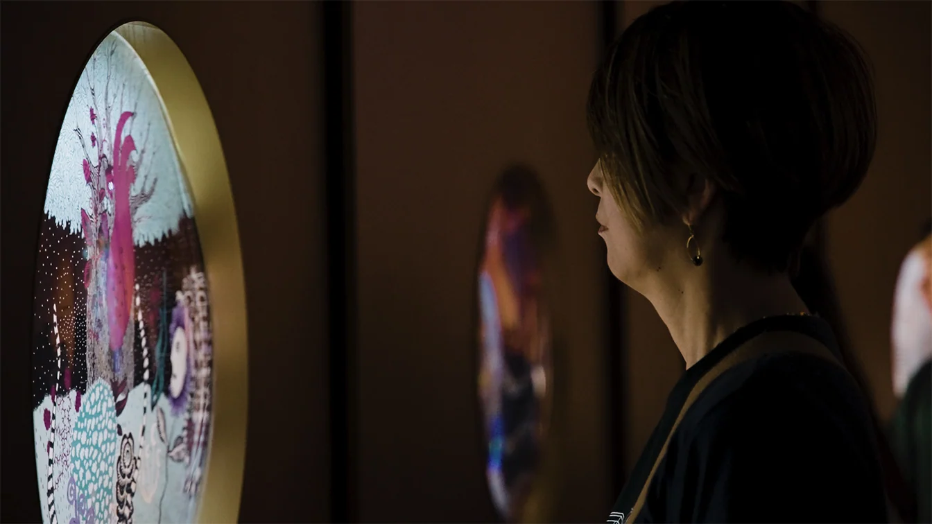 Visitor looking closely at animated floral imagery on a circular 7herbs display.