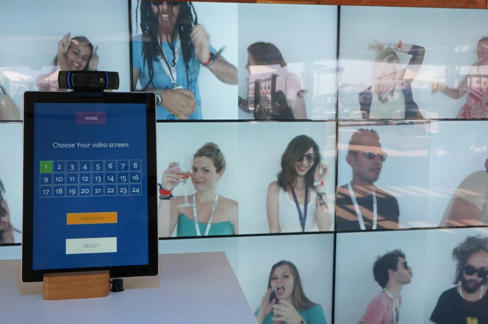 Touchscreen for choosing a video screen, with a camera and portrait wall behind it.