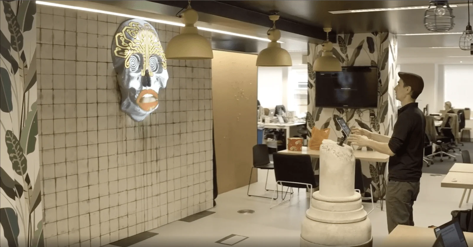Person gesturing towards an animated skull projection on an office wall.