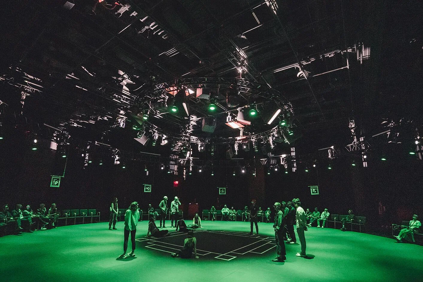 Visitors gathered around a central platform in the green-lit Kagami performance space.