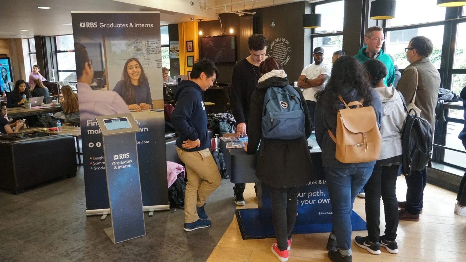 Crowd around an RBS graduate recruitment stand and interactive table.