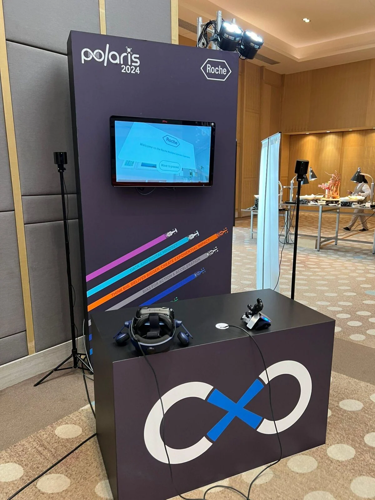Black Roche Polaris exhibition kiosk with a display, headsets and an illuminated infinity symbol.