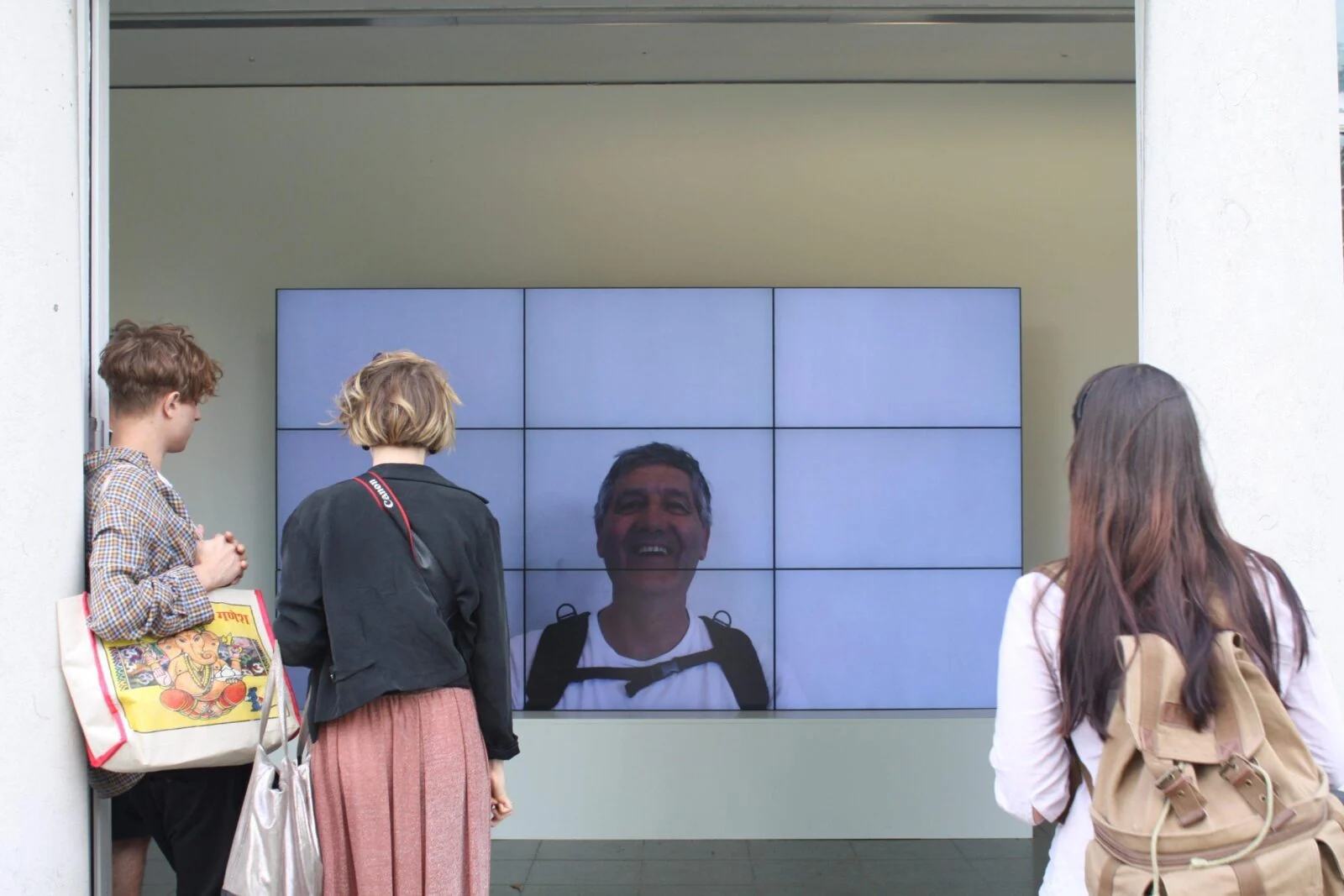Gallery visitors watching a smiling face on the Smiles Film video wall.